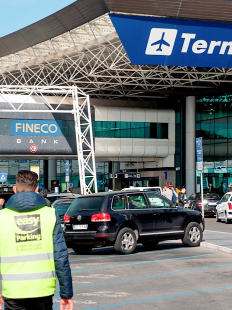 Fiumicino Airport Terminal 3 entrance with cars and travelers, Rome, Italy.