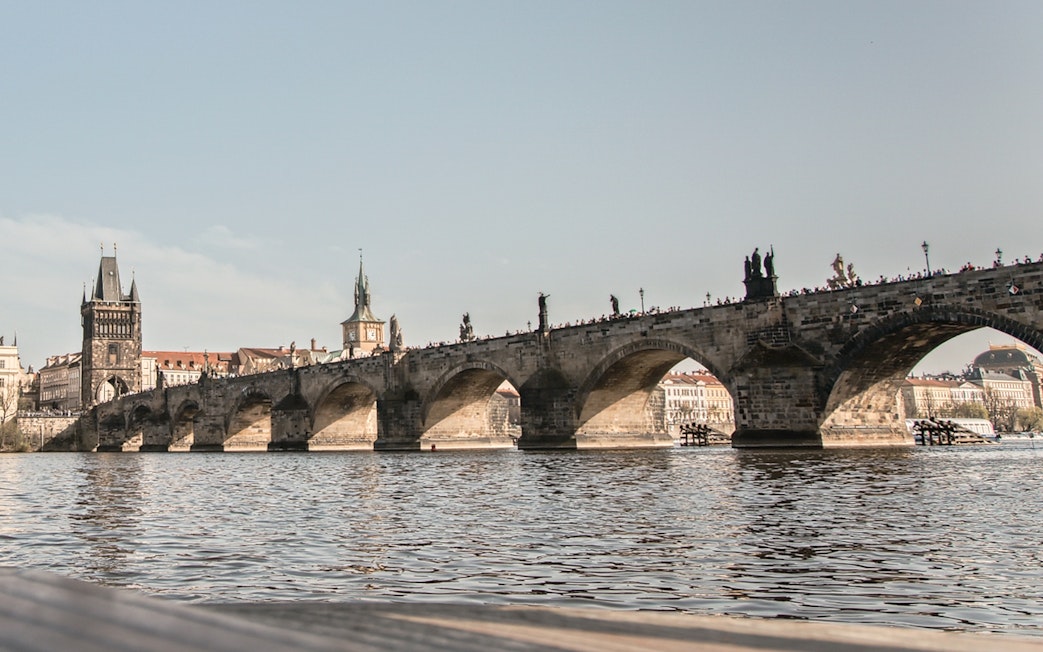 Charles Bridge over Vltava River in Prague Old Town with historic towers in view.