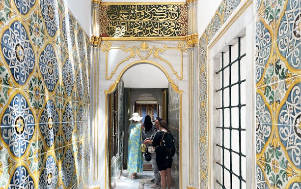 Visitors exploring ornate corridor in Topkapi Palace Harem, Istanbul.