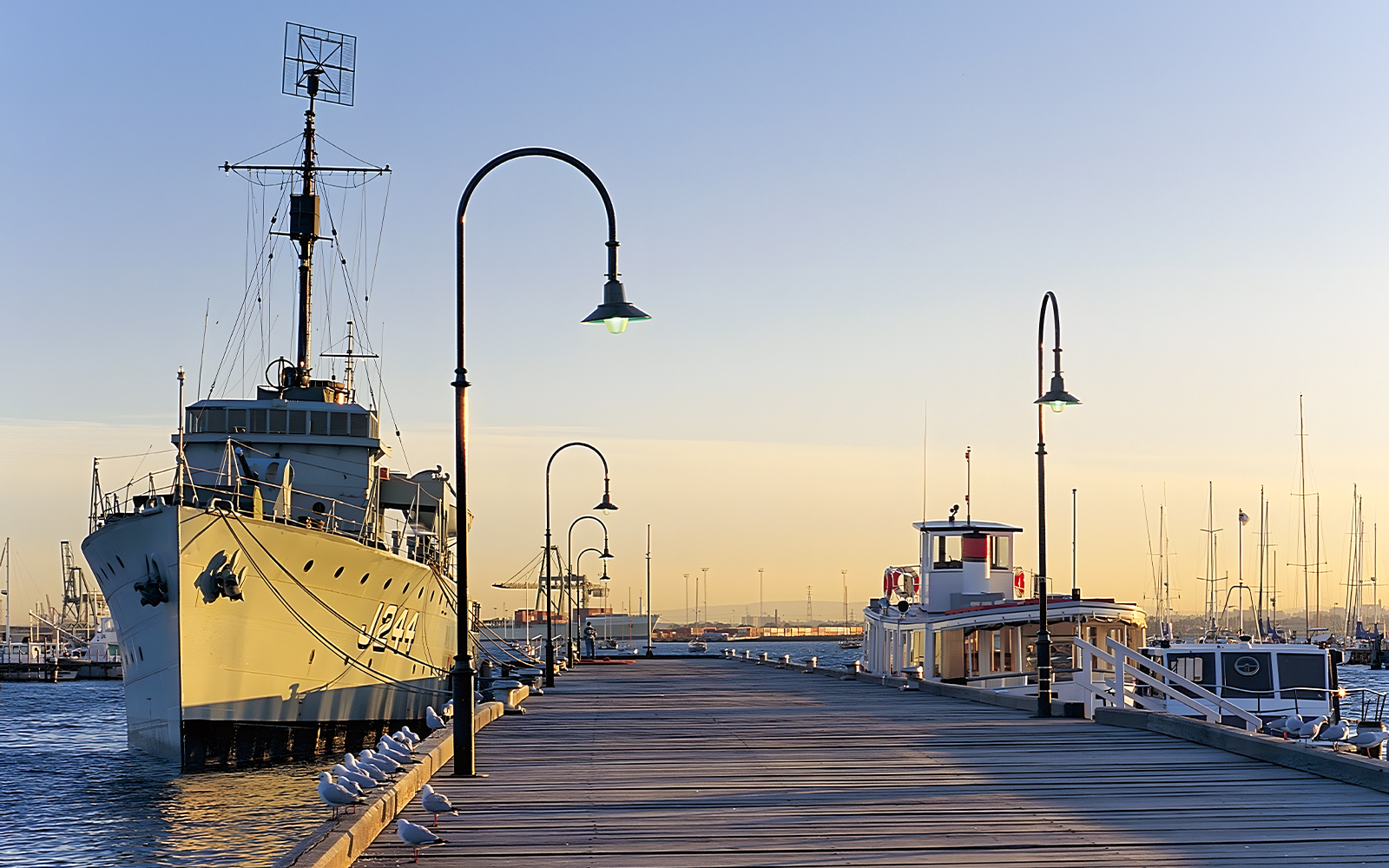 Historic ship docked at Gem Pier, Williamstown, with seagulls along the pier at sunset.