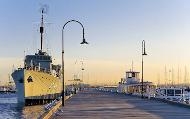 Historic ship docked at Gem Pier, Williamstown, with seagulls along the pier at sunset.