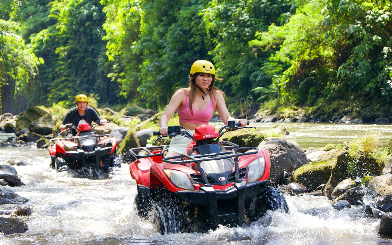 ATV riders crossing a river in Bali jungle during guided tour.