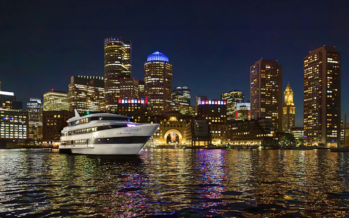 Premier Dinner Cruise ship on Boston Harbor with city skyline at night.