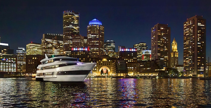 Premier Dinner Cruise ship on Boston Harbor with city skyline at night.