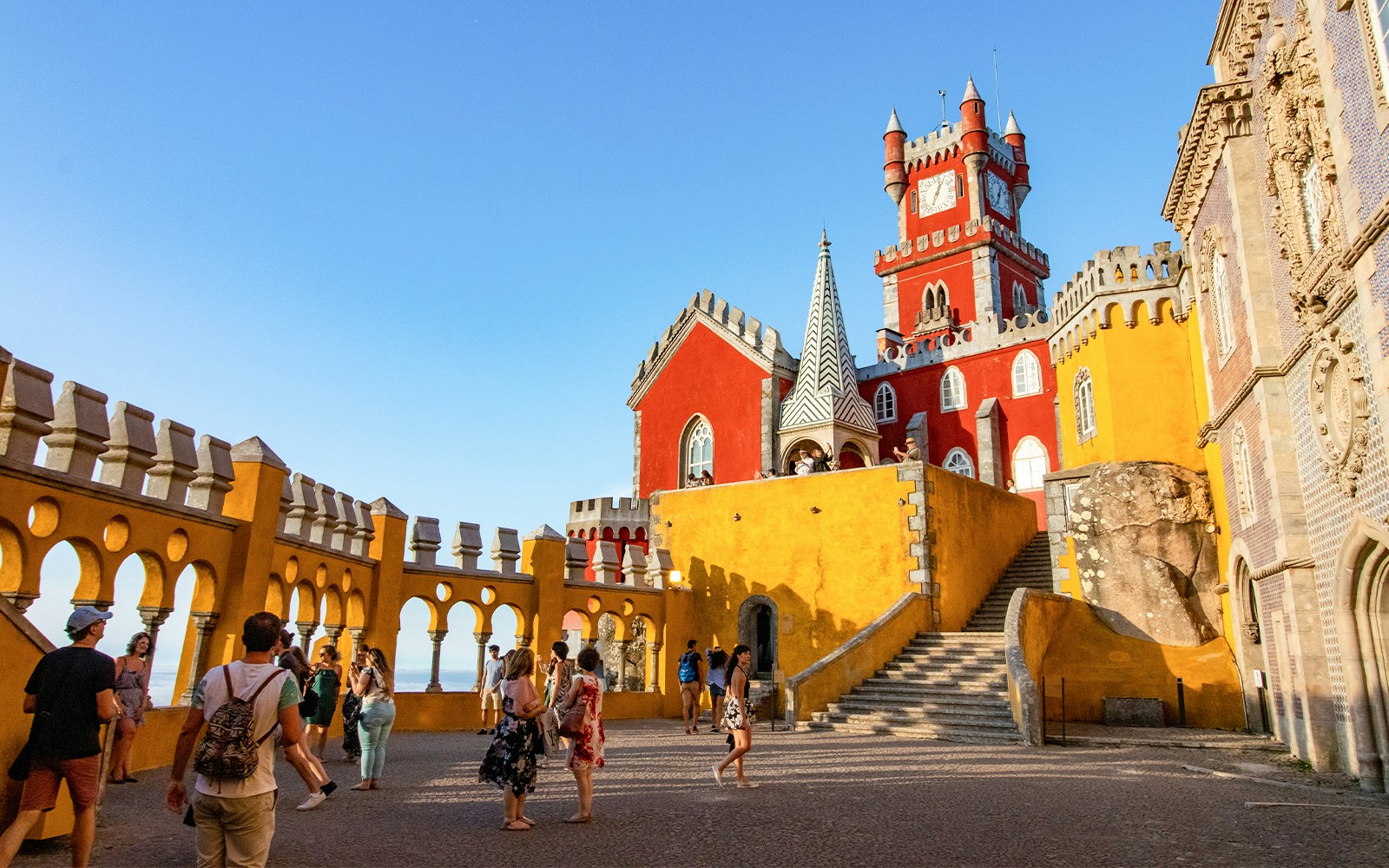Tourists exploring colorful towers of Pena Palace, Sintra, Portugal.