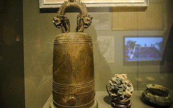 Ancient bronze bell with dragon motifs in Da Nang museum display.