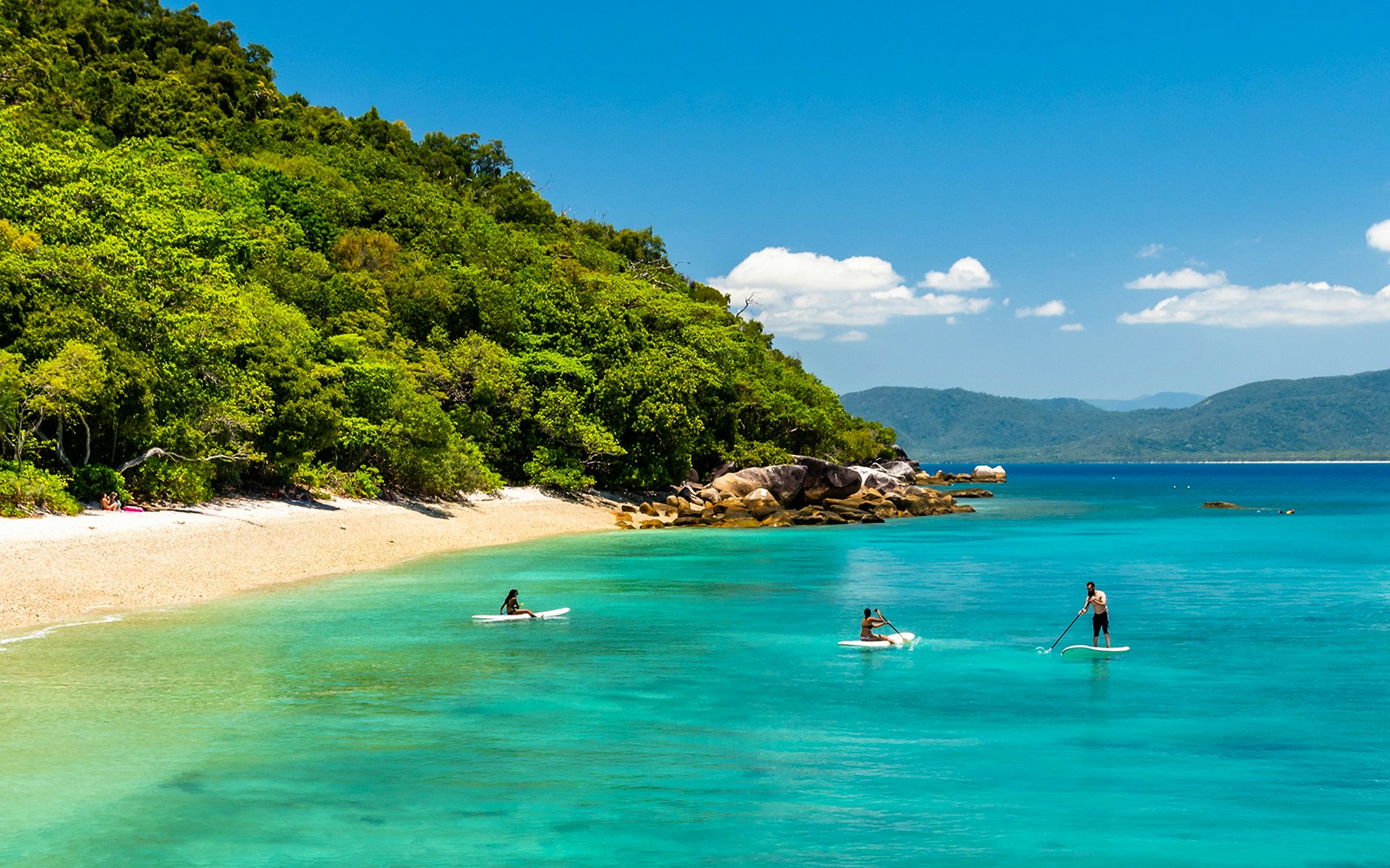 Group of tourists enjoying the Full Day Fitzroy Island Adventure Tour from Cairns, exploring the vibrant coral reefs and lush greenery of the island