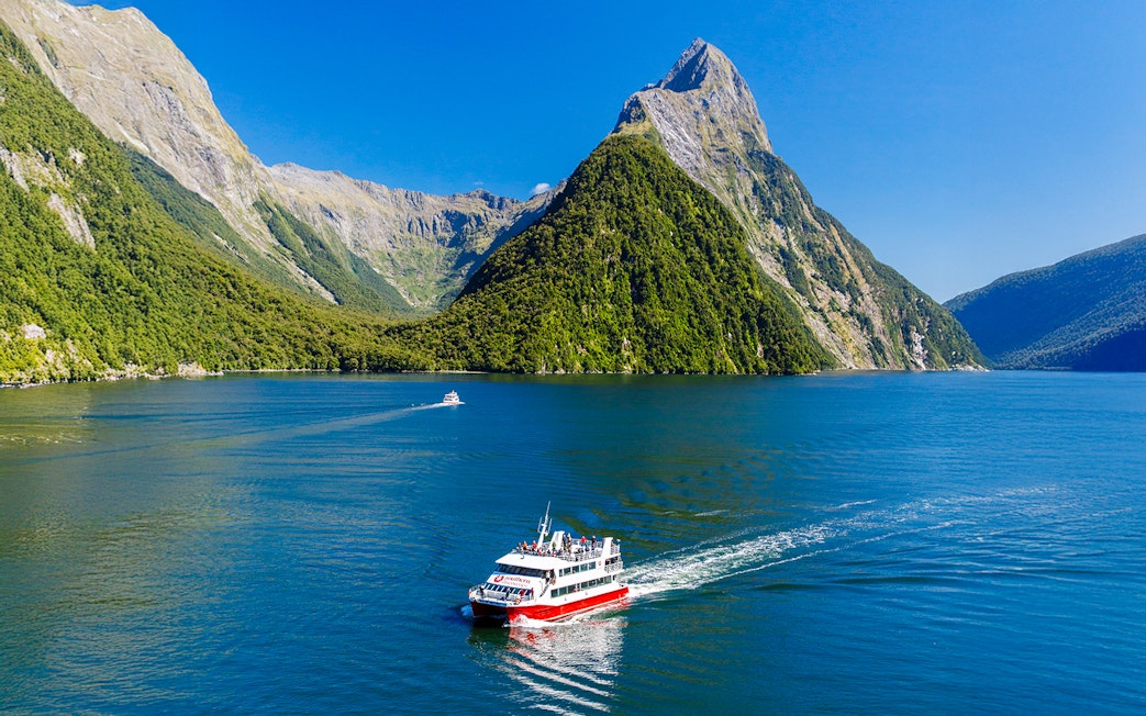 Cruise boat on Milford Sound with lush mountains, Southern Discoveries tour.