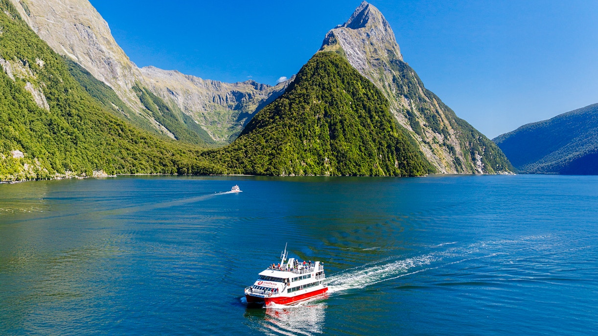 Cruise boat on Milford Sound with lush mountains, Southern Discoveries tour.