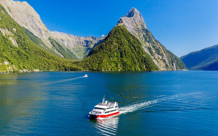 Cruise boat on Milford Sound with lush mountains, Southern Discoveries tour.