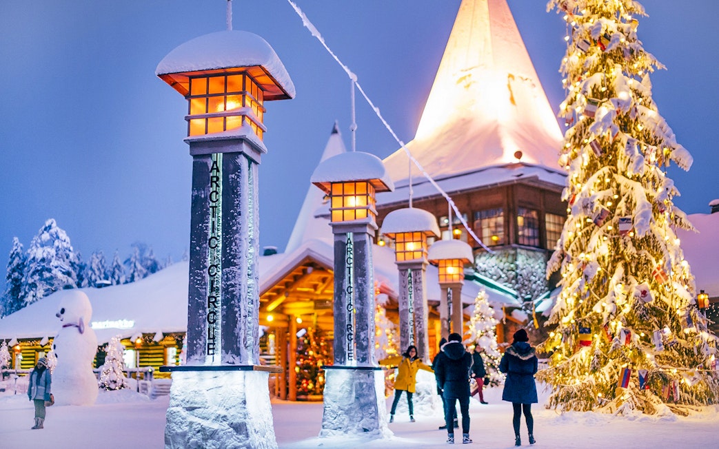 Santa Claus Village entrance with snow-covered pillars and Christmas tree, Rovaniemi.