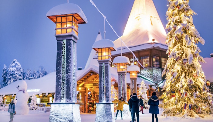 Santa Claus Village entrance with snow-covered pillars and Christmas tree, Rovaniemi.