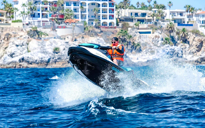 Jet skiing on the waves near Cannes, French Riviera, with coastal buildings in the background.