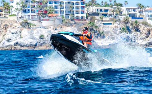 Jet skiing on the waves near Cannes, French Riviera, with coastal buildings in the background.