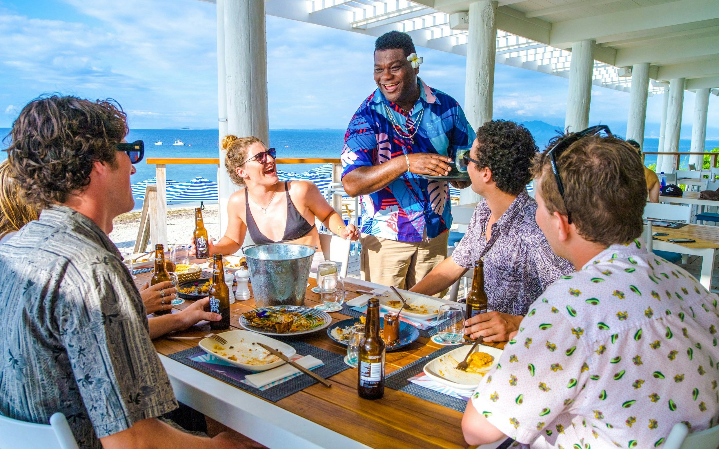 Man serving lunch and chatting with guests at Malamala Beach Club, Fiji.