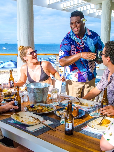 Man serving lunch and chatting with guests at Malamala Beach Club, Fiji.