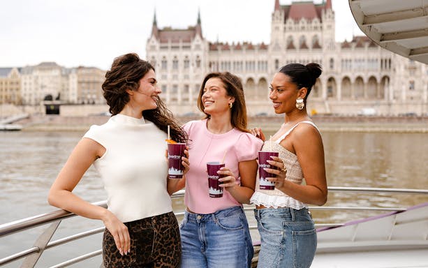 Guests enjoying drinks on a boat with Budapest Parliament in the background during Margaret Island Loop tour.
