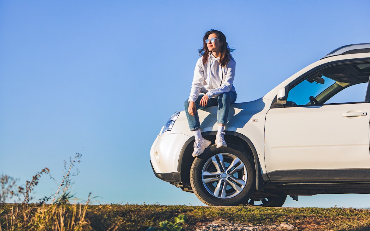 Person sitting on a white SUV under a clear blue sky in Langkawi.