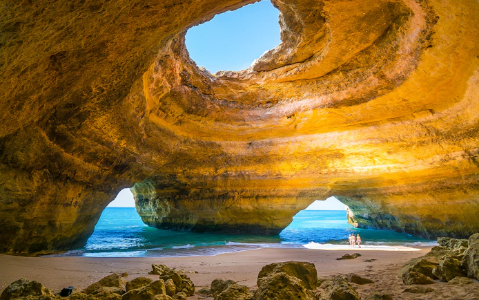Benagil Caves with sunlight through rock formations and ocean view.