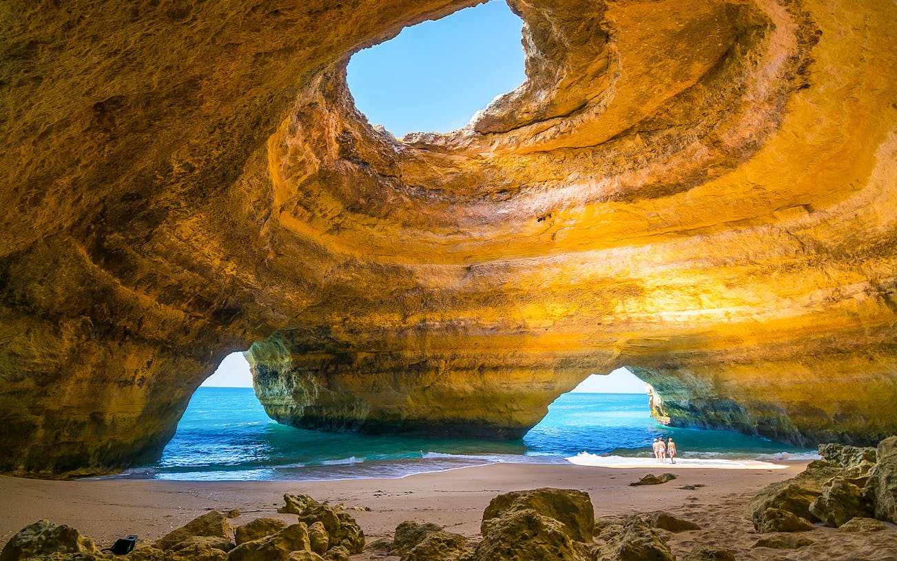 Benagil Caves with sunlight through rock formations and ocean view.