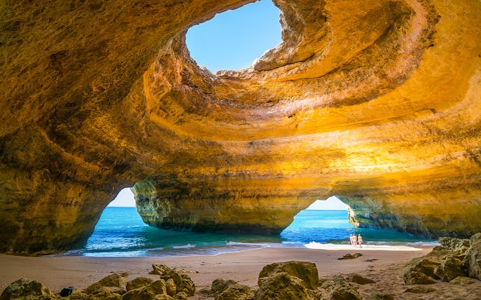 Benagil Caves with sunlight through rock formations and ocean view.