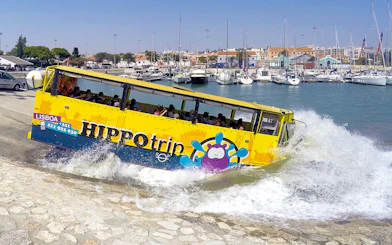 Amphibious tour bus entering water in Lisbon marina during sightseeing tour.