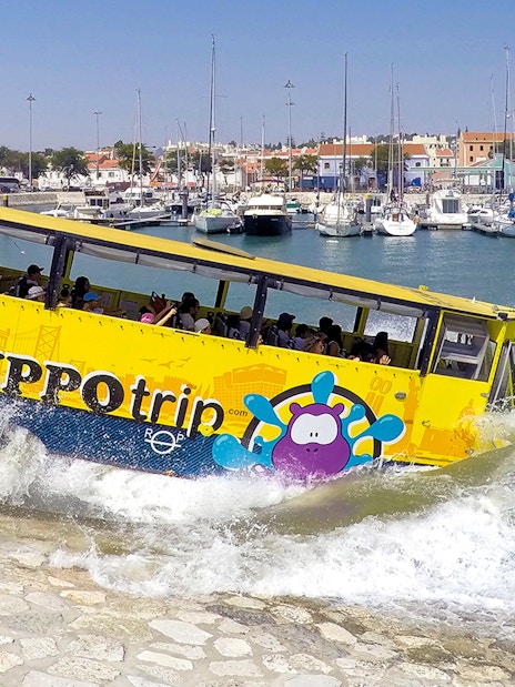 Amphibious tour bus entering water in Lisbon marina during sightseeing tour.