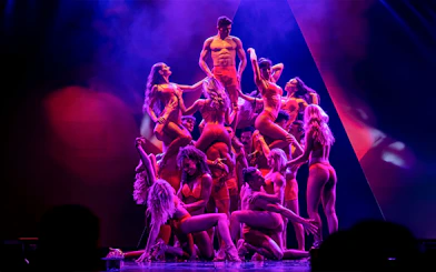 Performers in red costumes forming a pyramid on stage during the Rouge show.