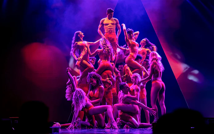 Performers in red costumes forming a pyramid on stage during the Rouge show.