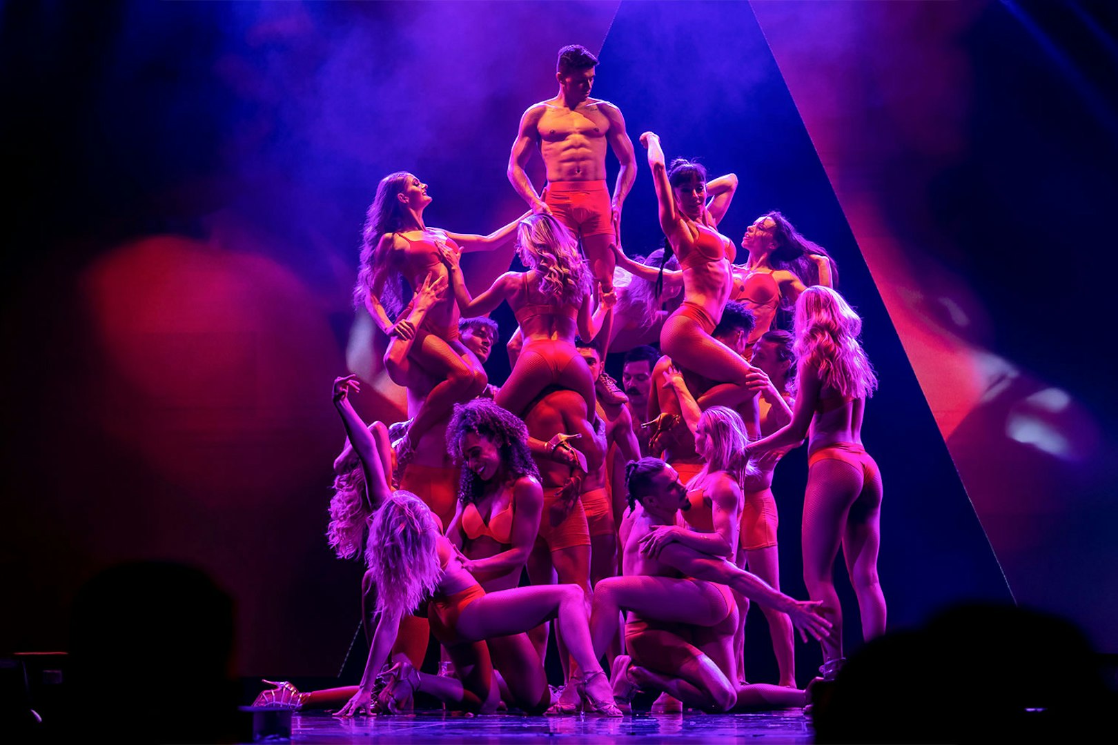 Performers in red costumes forming a pyramid on stage during the Rouge show.