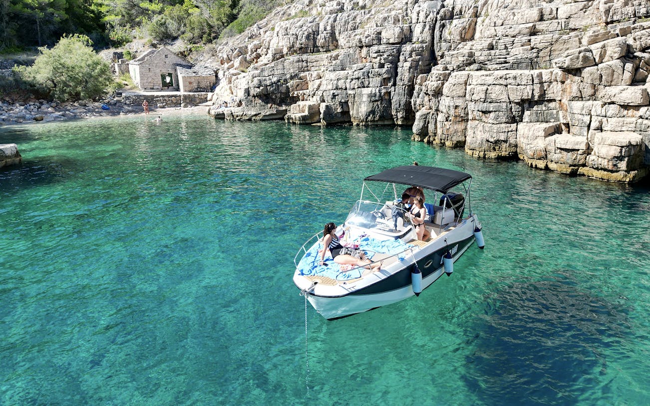 Speedboat with tourists on clear waters near rocky shore, North Shore of Hvar Island.
