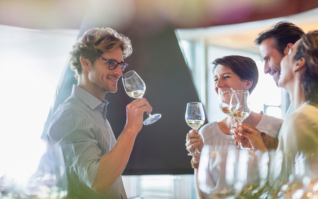 Friends enjoying a white wine tasting experience indoors.