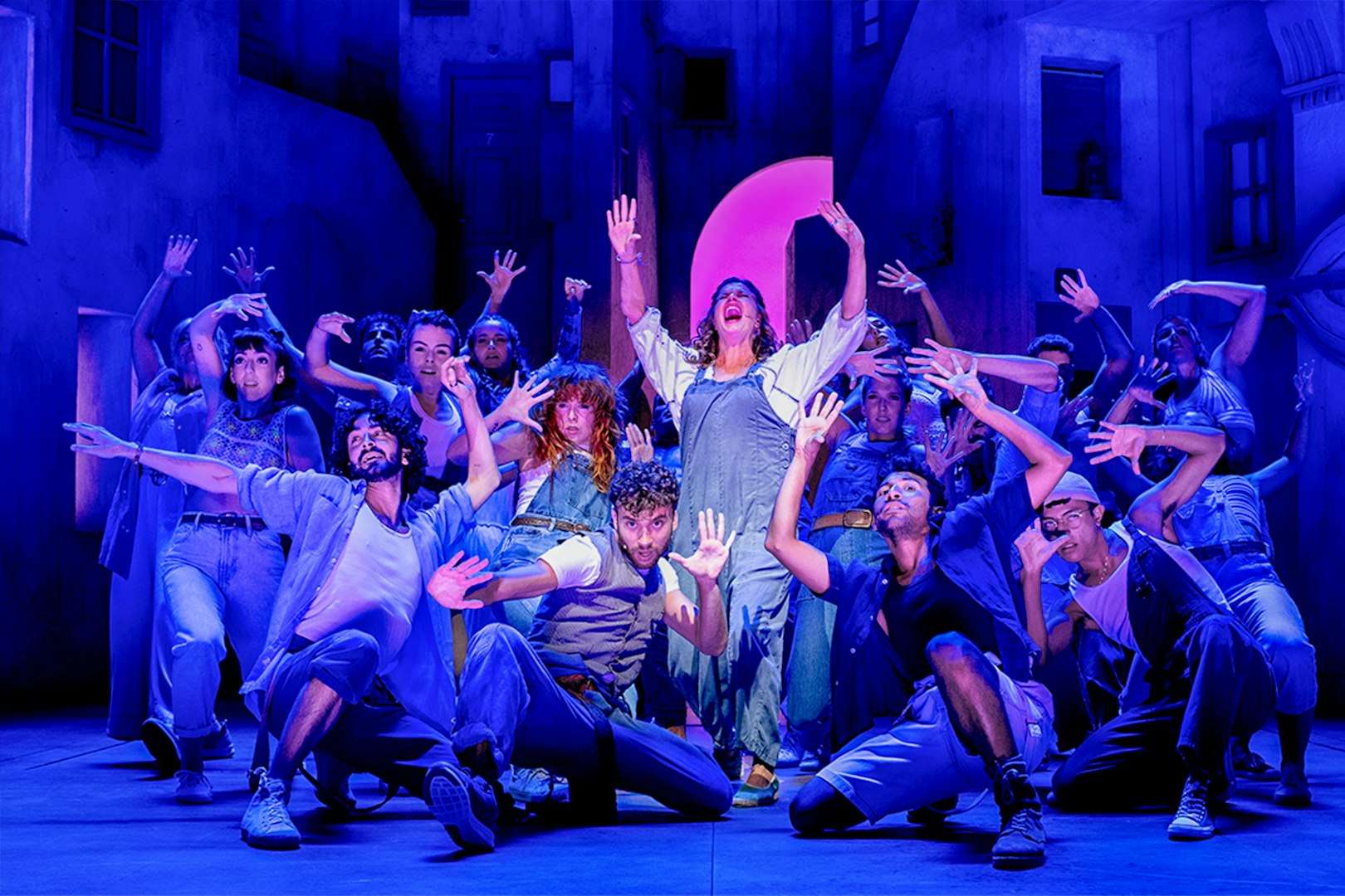 Performers on stage during MAMMA MIA! El Musical, with vibrant choreography and expressive poses.