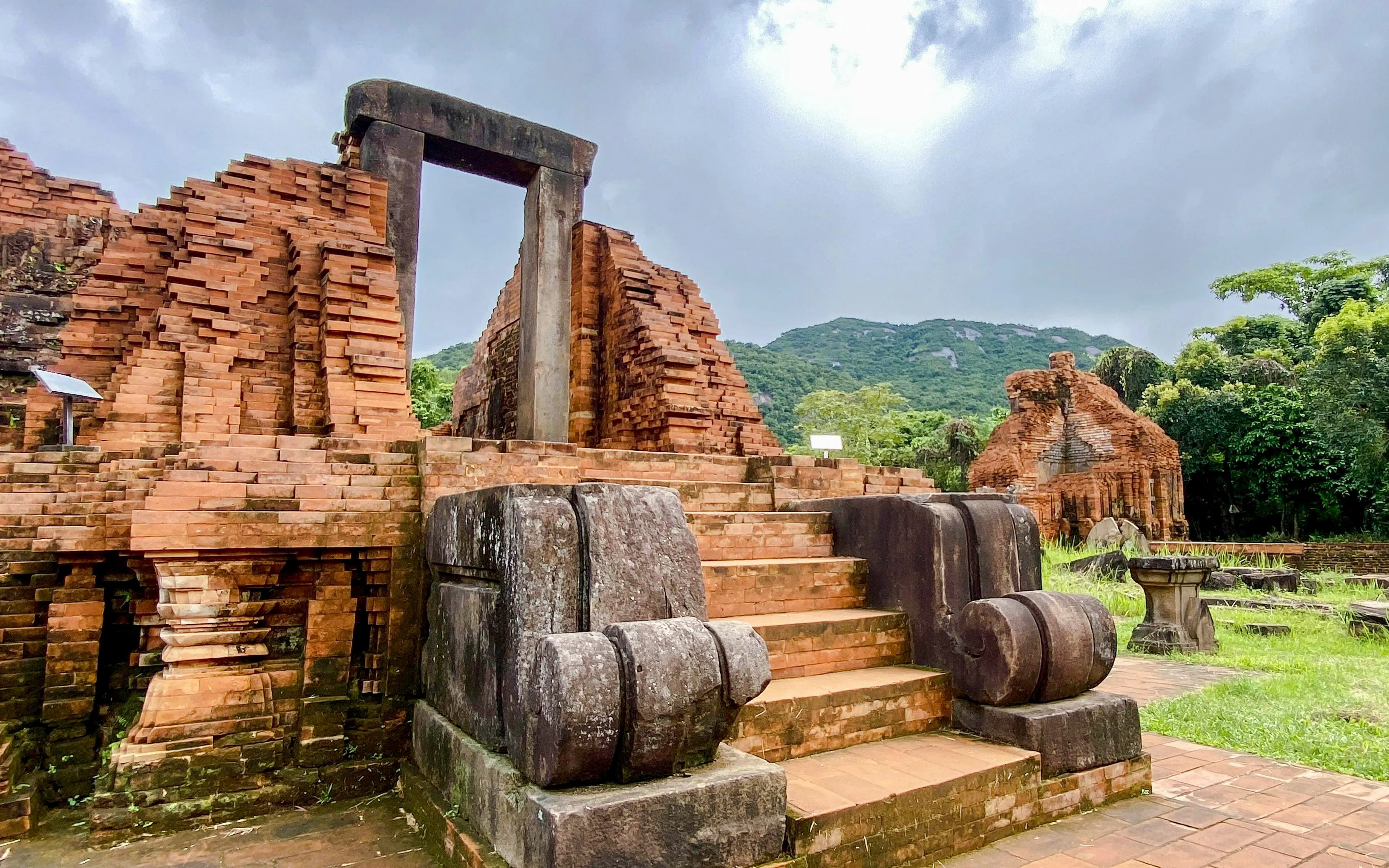 Ancient brick ruins at My Son Sanctuary, Danang, Vietnam, with lush green hills in the background.