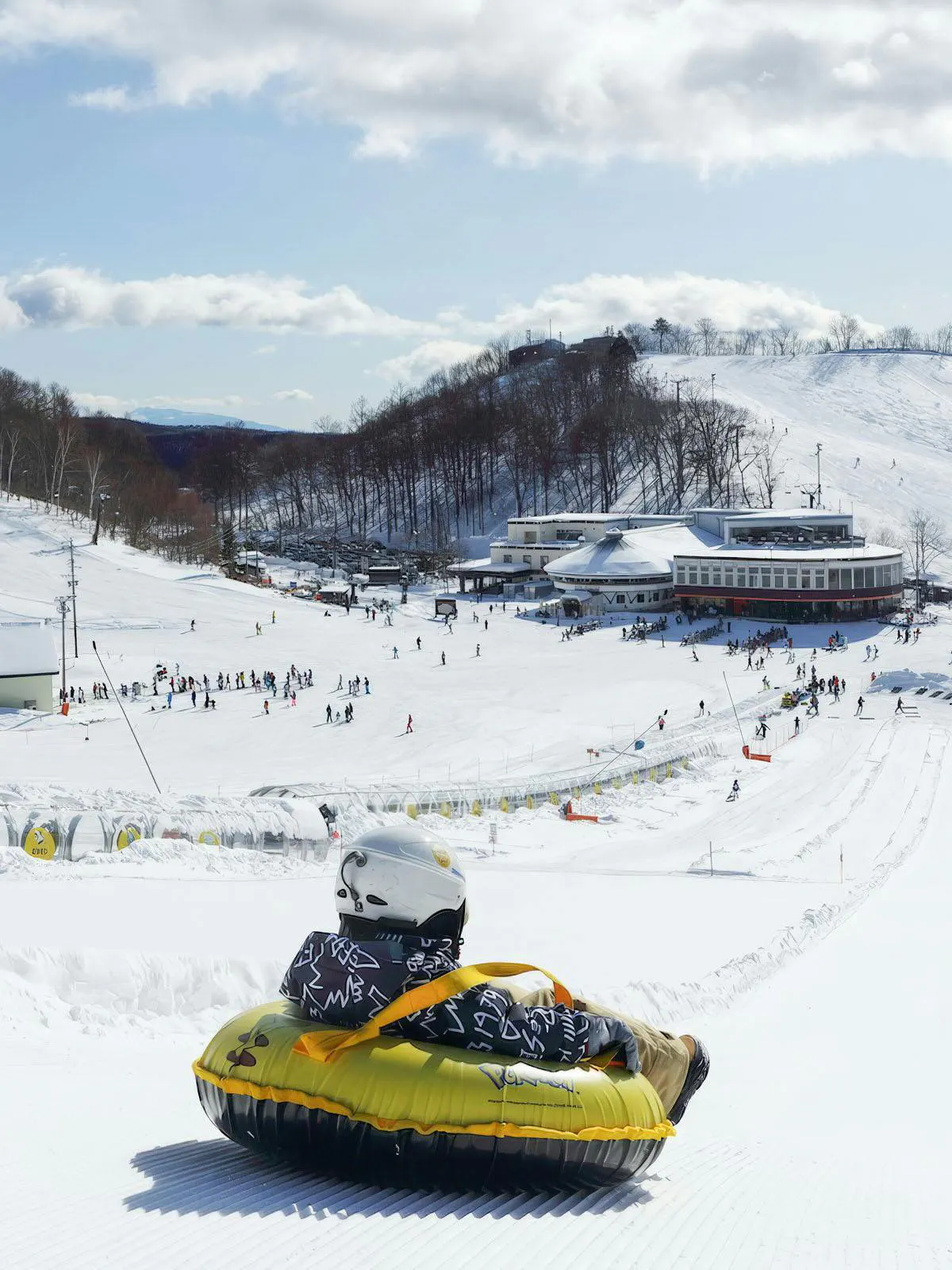 Person tubing down snowy slope at Hakuba Kashimayari Ski Resort, Japan.