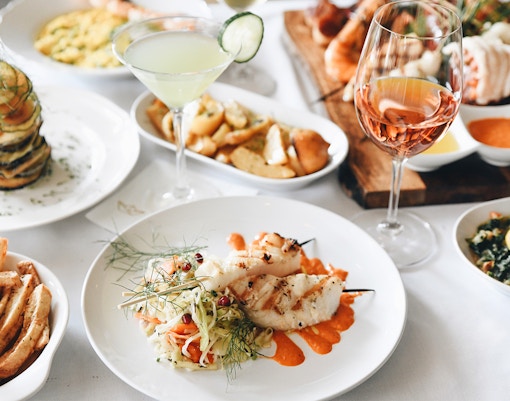 Mediterranean lunch with grilled fish skewers, vegetable stack, and wine.