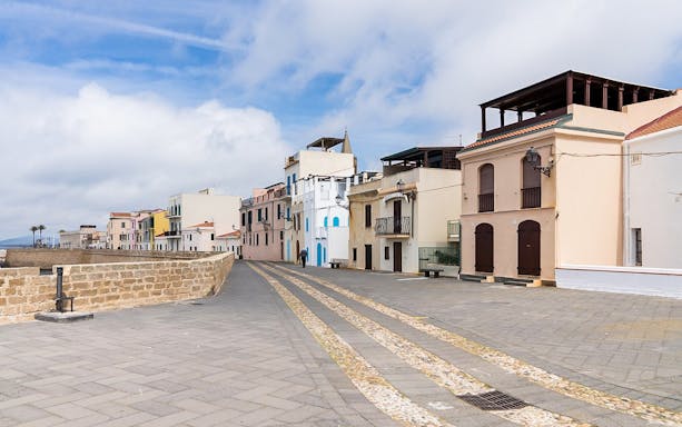 Alghero historic center street with colorful buildings and stone walkway.