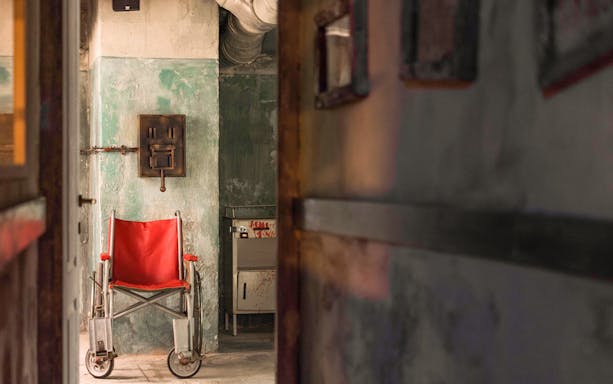 Red wheelchair in dimly lit room at Neverland Bar & Escape Room.