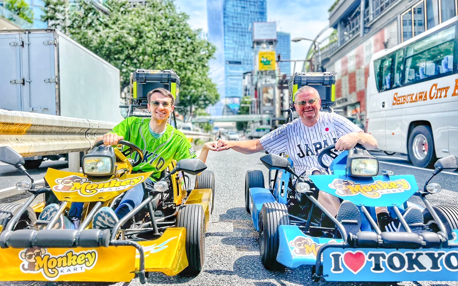 Two men in yellow and blue go-karts on a Tokyo street.