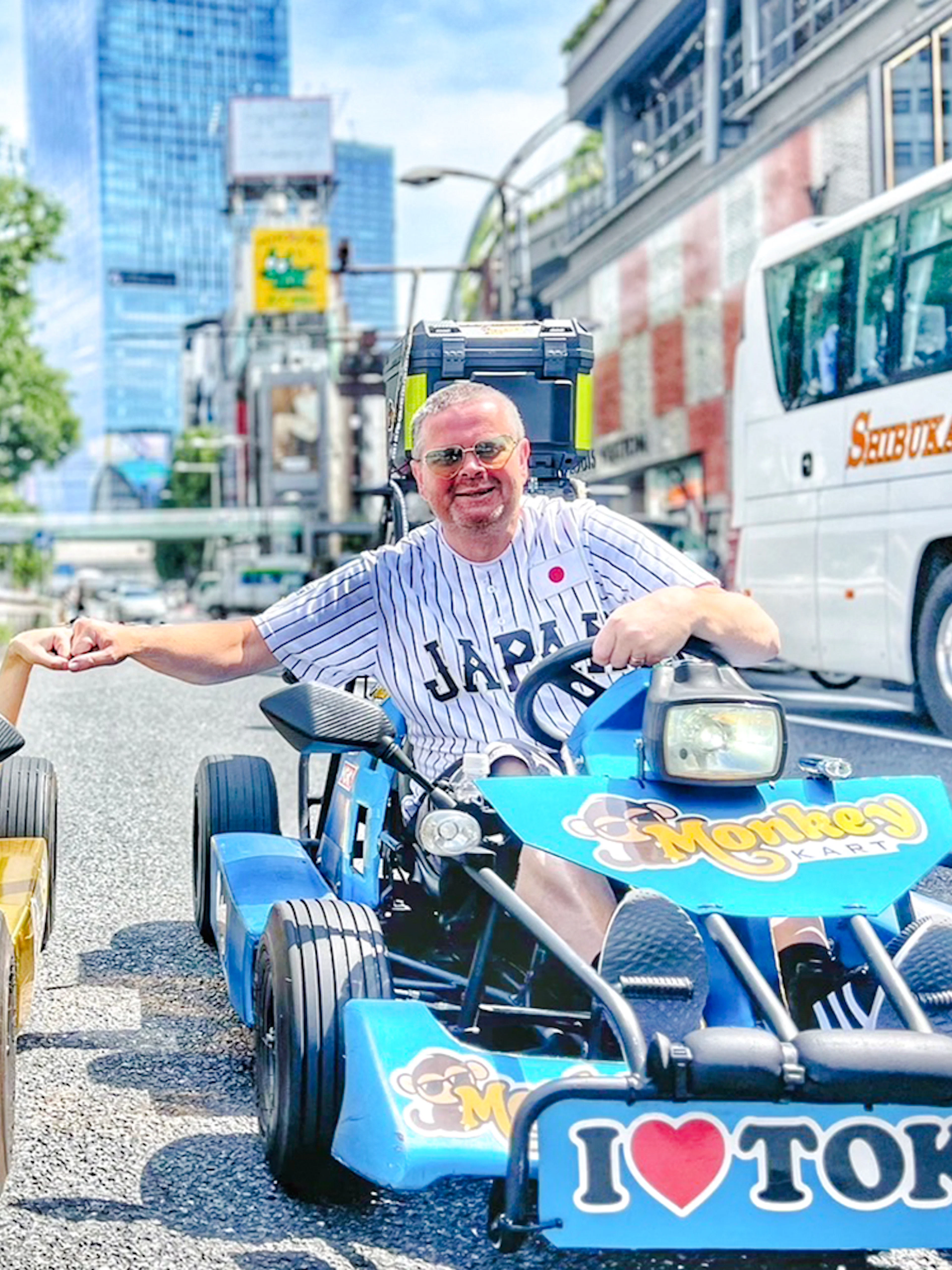 Two men in yellow and blue go-karts on a Tokyo street.
