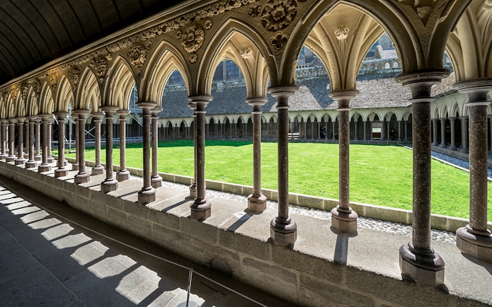 Cloister arches and green courtyard at Mont Saint Michel, France.