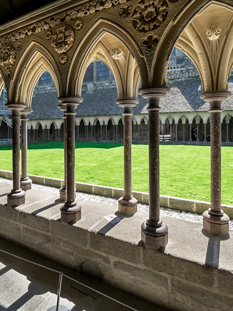 Cloister arches and green courtyard at Mont Saint Michel, France.