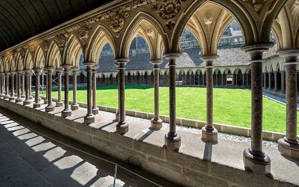 Cloister arches and green courtyard at Mont Saint Michel, France.
