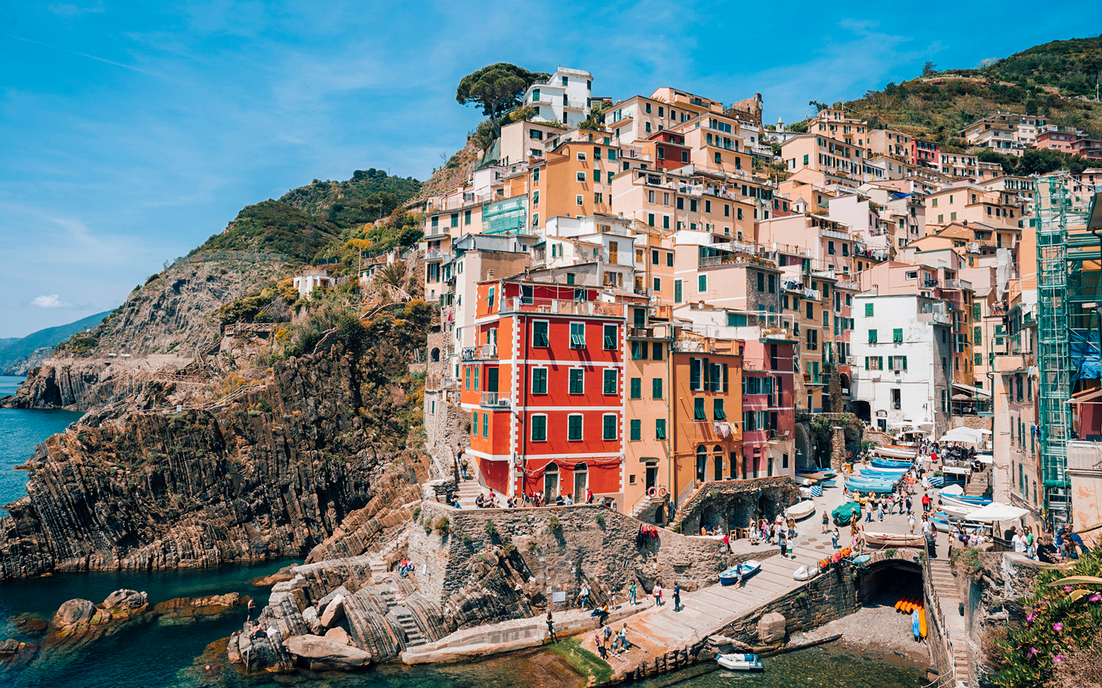 Riomaggiore Village in Italy with colorful cliffside houses and boats in the harbor.