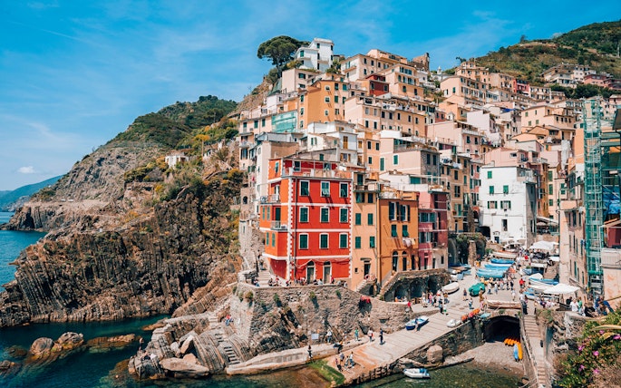Riomaggiore Village in Italy with colorful cliffside houses and boats in the harbor.