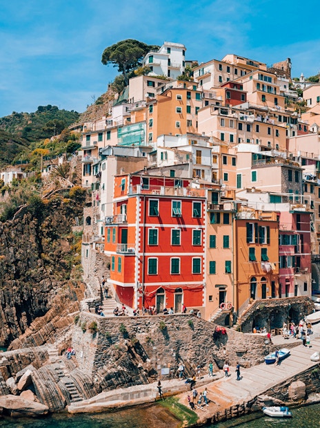 Riomaggiore Village in Italy with colorful cliffside houses and boats in the harbor.