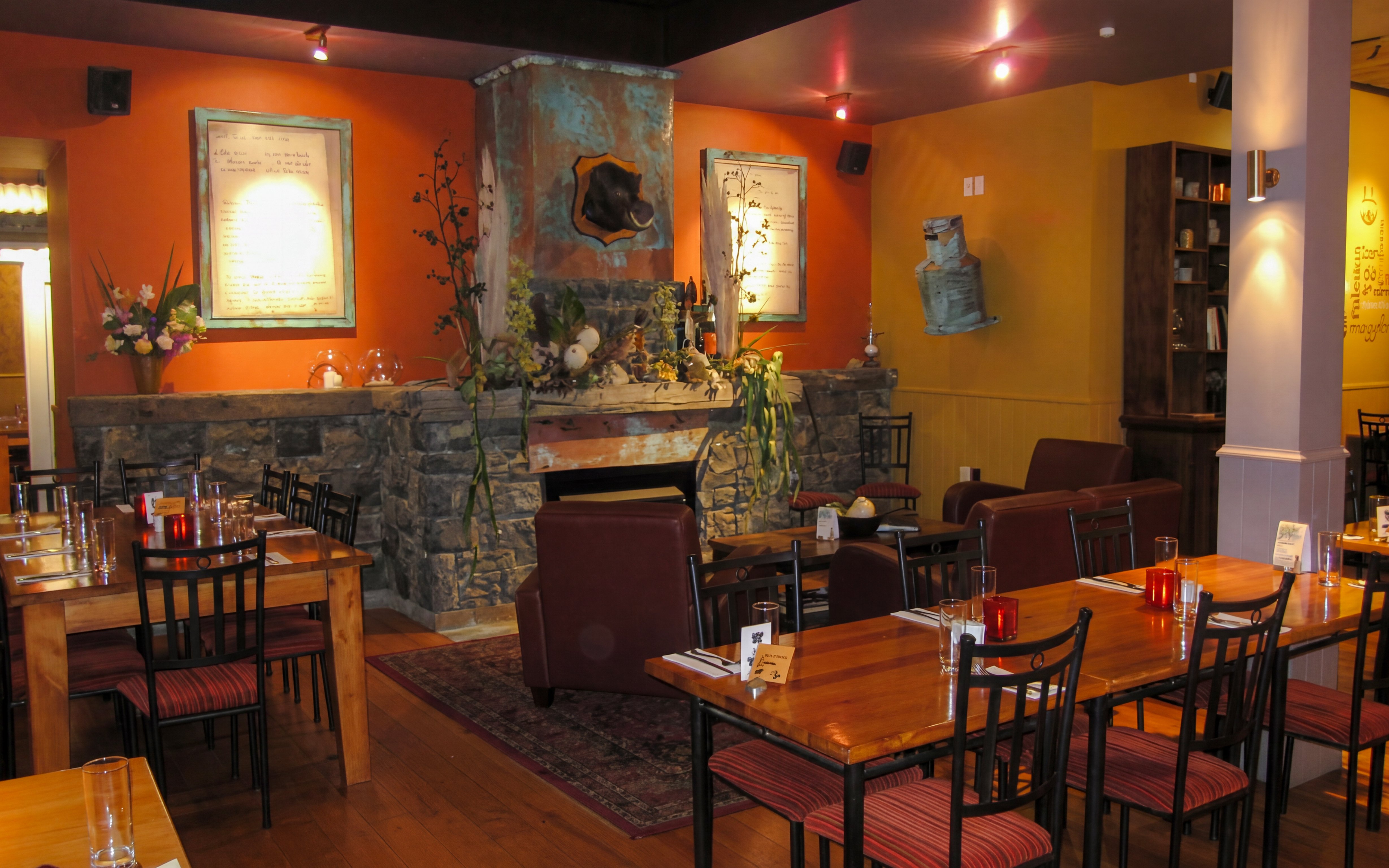 Riverhead Tavern interior with stone fireplace and dining tables set for guests.