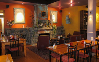 Riverhead Tavern interior with stone fireplace and dining tables set for guests.