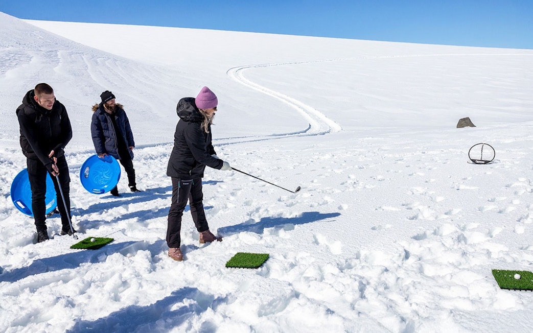 Guests playing golf on snow during Red Glacier Monster Truck Tour.