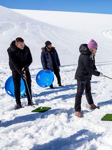 Guests playing golf on snow during Red Glacier Monster Truck Tour.